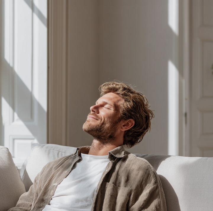 Person som kopplar av i soffa i ett ljust vardagsrum med balanserad ventilation från Flexit