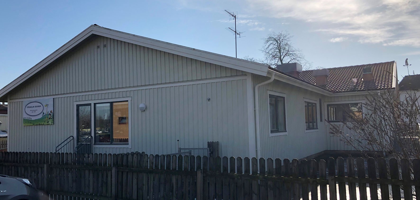 Exteriör av Grundens förskola, ljus träbyggnad med staket och entré, en trygg miljö med fokus på hälsosamt inomhusklimat.