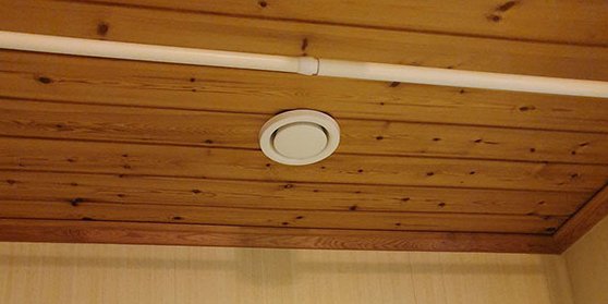 Frånluftsventil monterad i trätak i badrum som säkerställer effektiv bortförsel av fuktig luft.