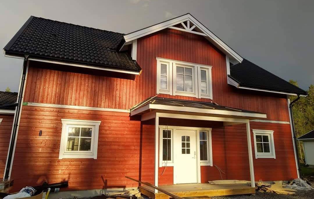 Röd tvåplansvilla med vit entré och svarta takpannor, Villa Sandnabba där EcoNordic har installerats för energieffektiv ventilation och uppvärmning.