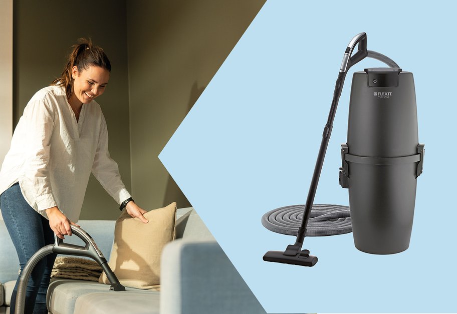 Person støvsuger sofa i stue med slange tilkoblet sentralstøvsuger.