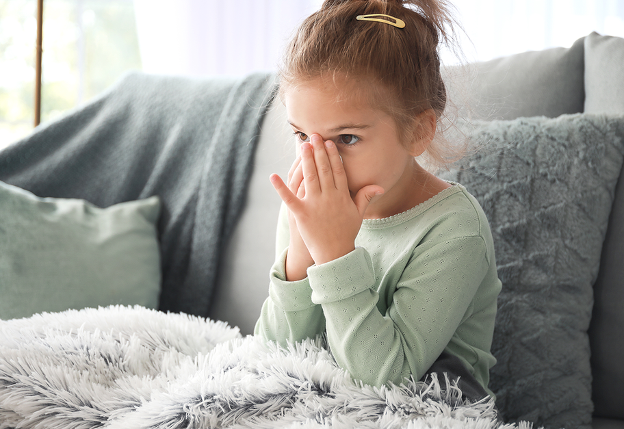Barn som sitter inne og holder seg for nesen i et lunt miljø.