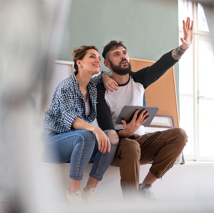 Par sitter på gulv med nettbrett og planlegger oppussing sammen i lyst rom