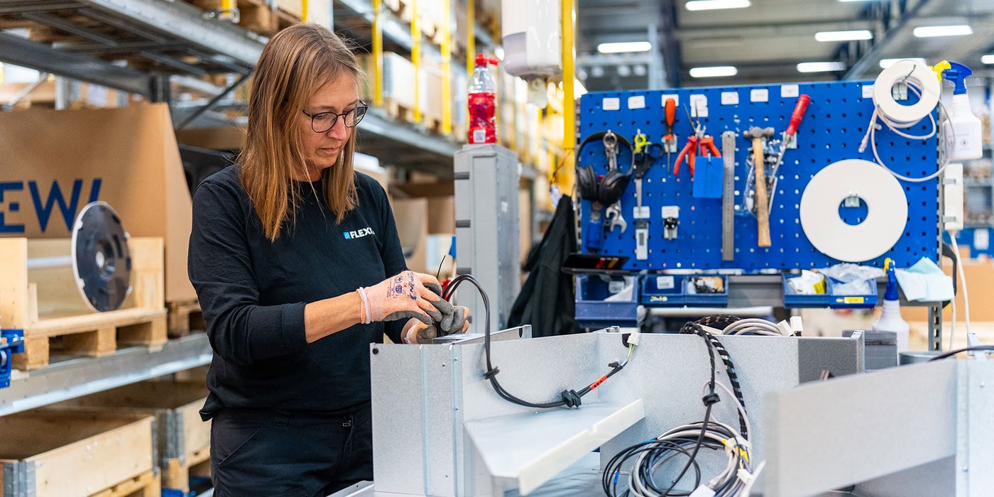 Medarbeider som monterer komponenter i produksjonshall.