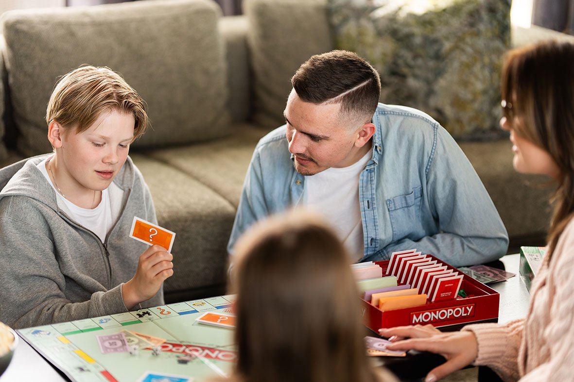 Familie som spiller brettspill i et lunt og behagelig innemiljø.