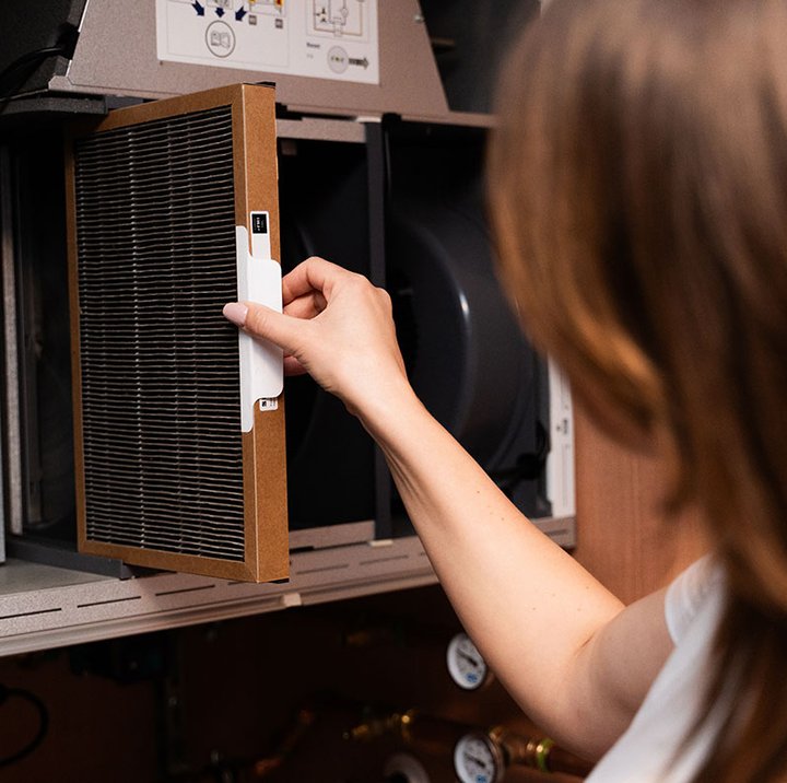 Person tar ut ventilationsfilter från ett Flexit ventilationsaggregat för underhåll.