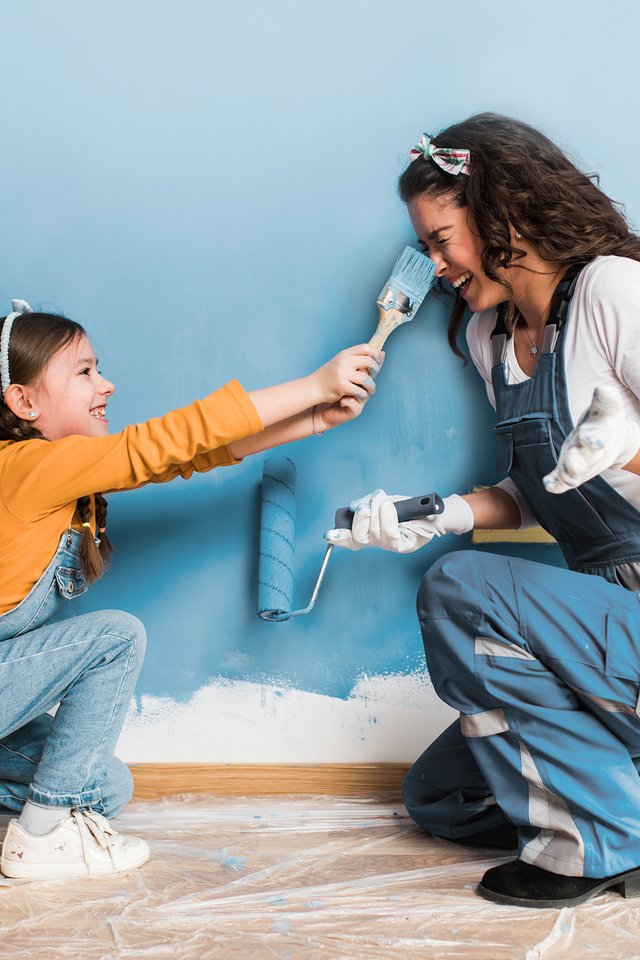 Child and adult painting wall in ventilated indoor space