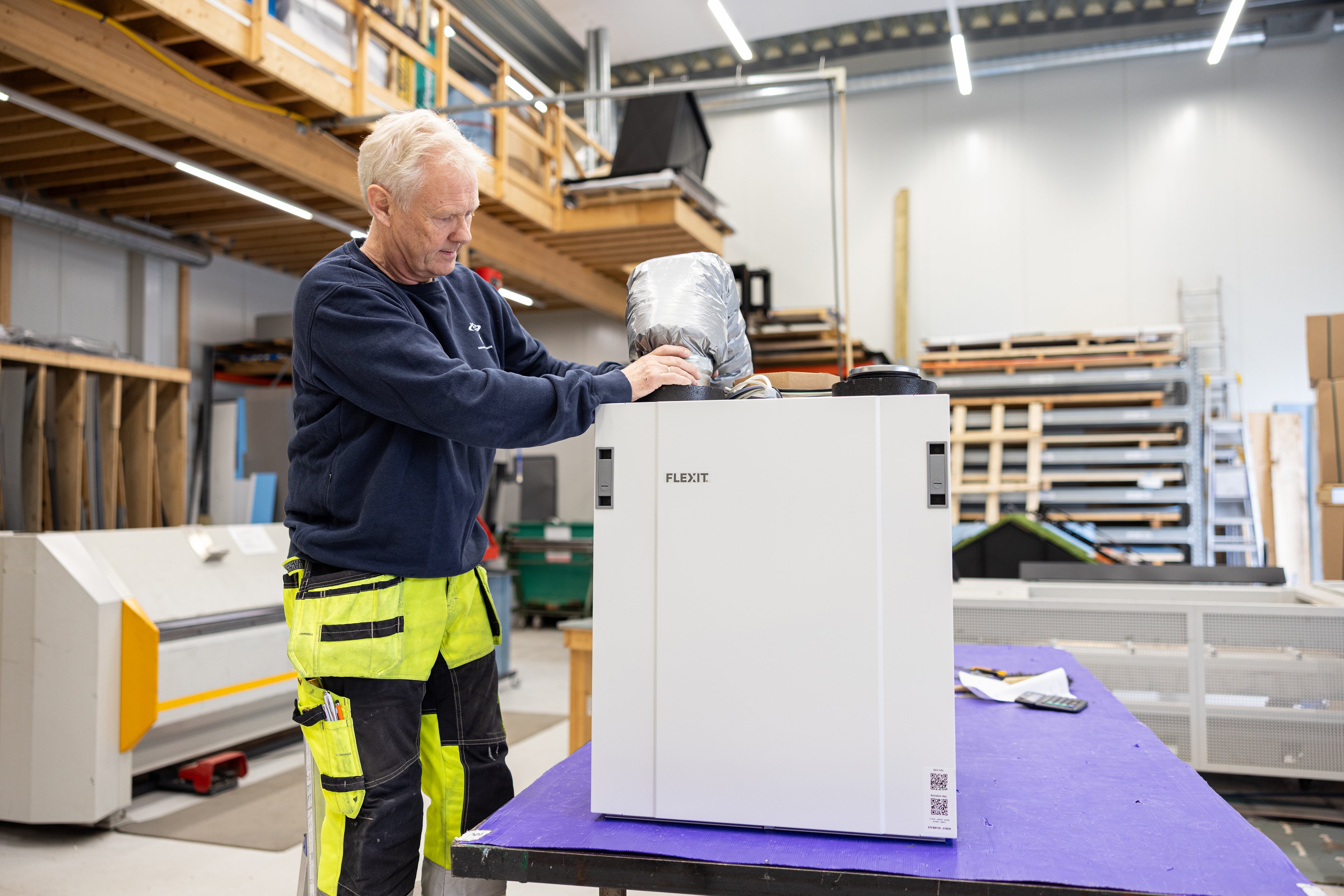 Montør fra Salvesen Blikk og Ventilasjon installerer et Flexit ventilasjonsaggregat i verksted.